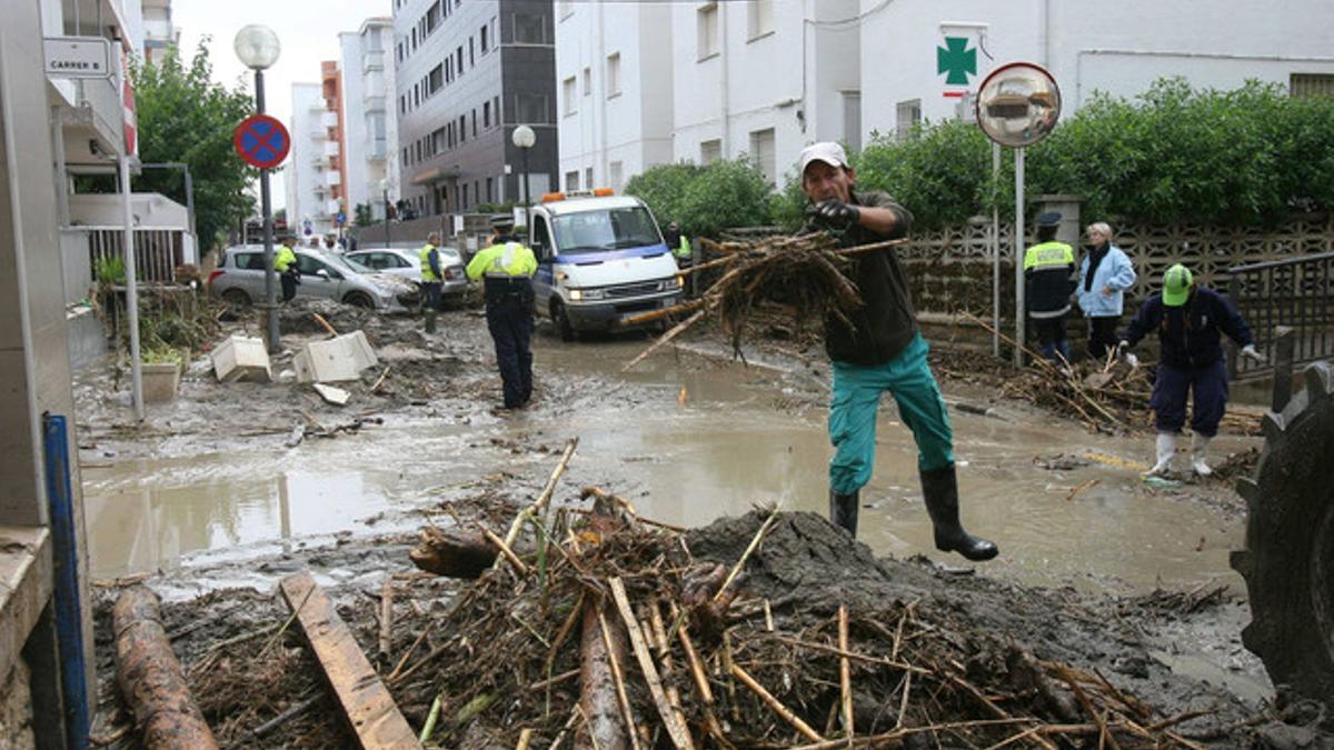 Un operario retira material arrastrado por la lluvia en la riera de Barenys, en Salou.