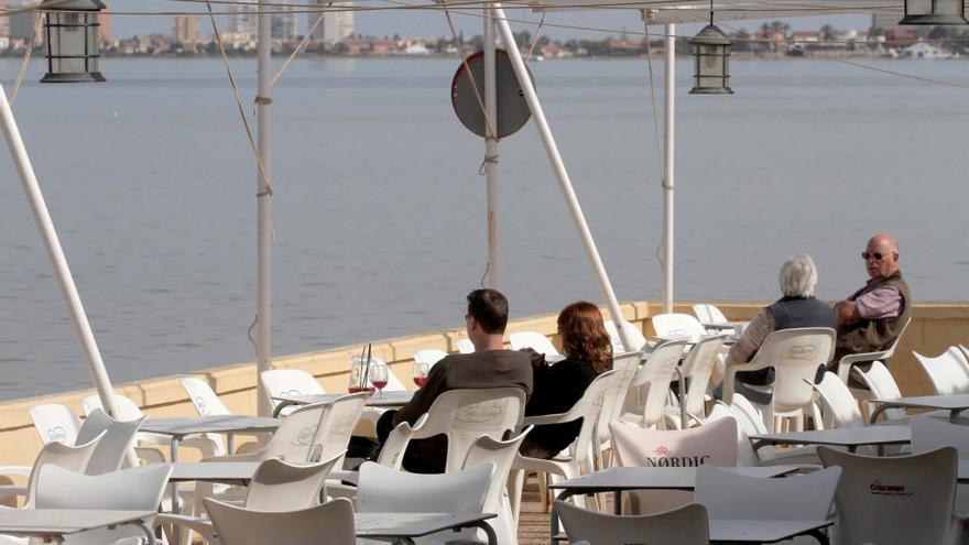 Varias personas toman el aperitivo frente al mar en invierno.