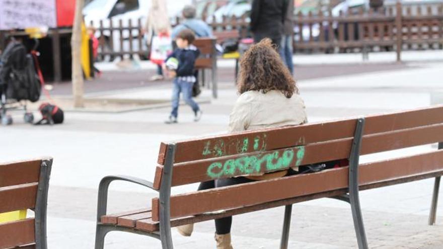 Una mujer sentada en un banco mientras observa un parque infantil de la capital.