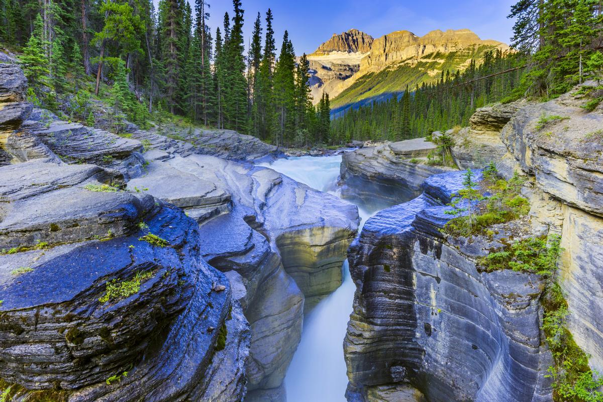 Mistaya Canyon, ubicado en las Montañas Rocosas de Canadá, es un impresionante desfiladero tallado por el caudaloso río Mistaya. Se encuentra en el Parque Nacional Banff y destaca por sus formaciones de piedra caliza erosionada y su fácil acceso. El término "Mistaya" proviene del idioma nativo cree (mistahaya), que se traduce al español como "oso pardo".