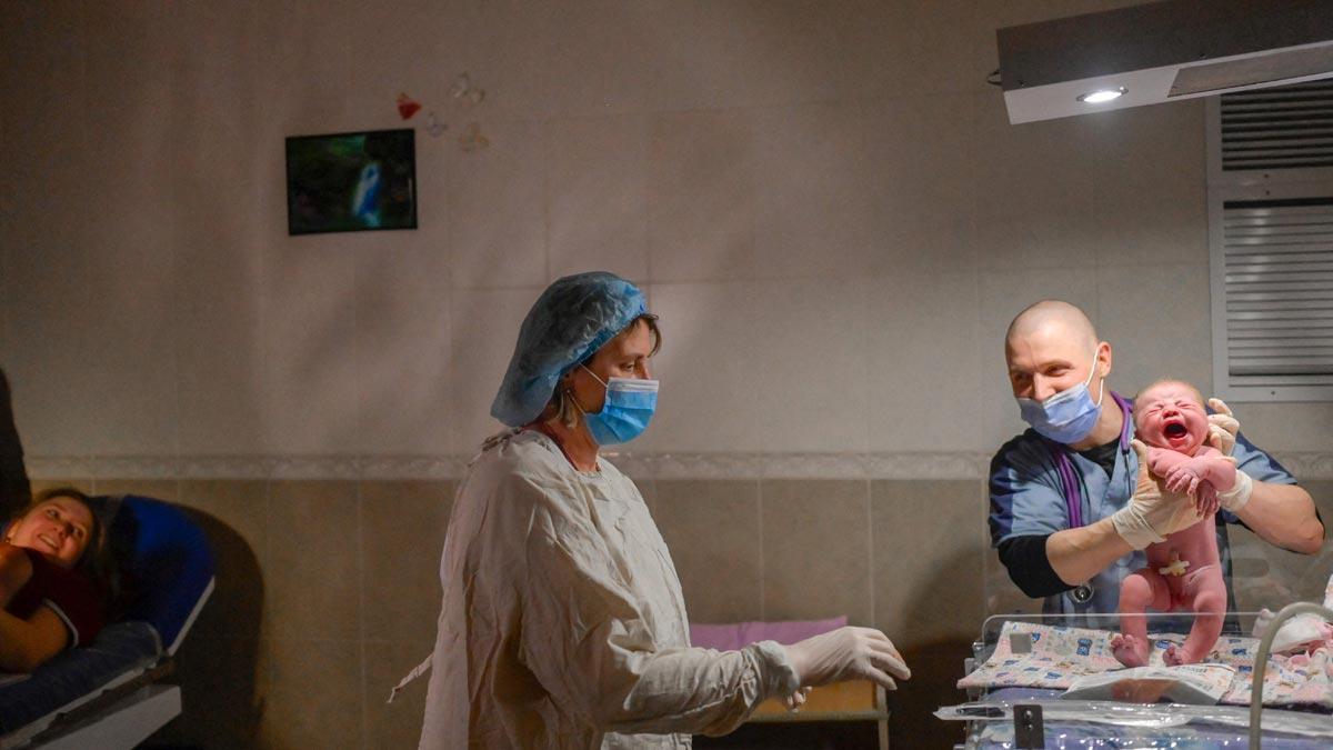 Aleina, a la izquierda, mira cómo los sanitarios sostienen a su bebé, Snizhana, segundos después de dar a luz en la maternidad de Mikolaiv, entre ruido de sirenas anunciando bombardeos.