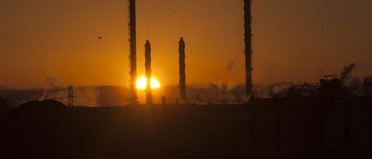 Una puesta de sol con las chimeneas de la fábrica de Asturiana de Zinc silueteadas por la luz crepuscular.