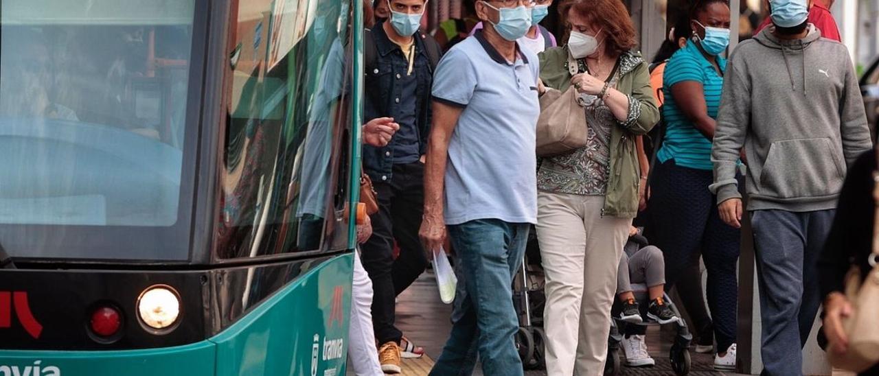 Varias personas con mascarilla en una parada del tranvía en Santa Cruz.