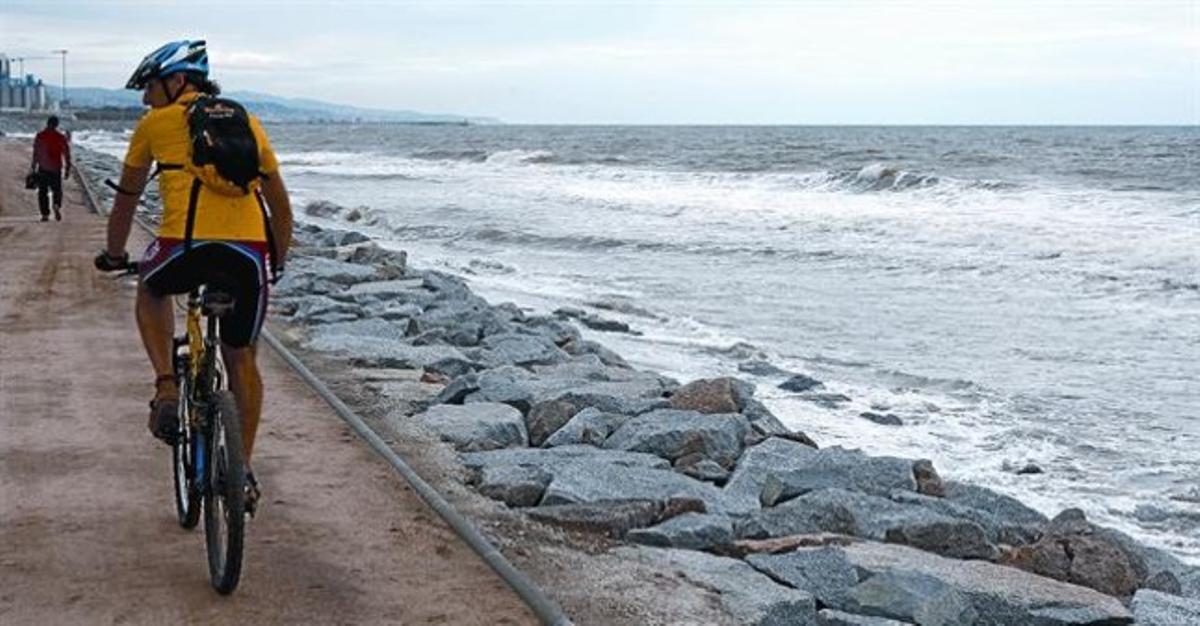 Un ciclista circula a la vora al mar, ahir, a Cabrera de Mar (Maresme), on la platja ha desaparegut sota la marea.