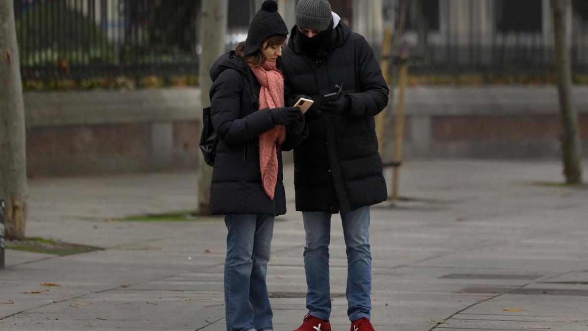 Dos viandantes bien protegidos del frío pasean por el parque del Retiro.