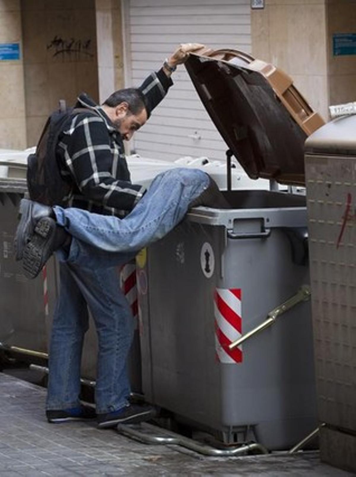 Dos homes busquen restes de menjar en un contenidor.
