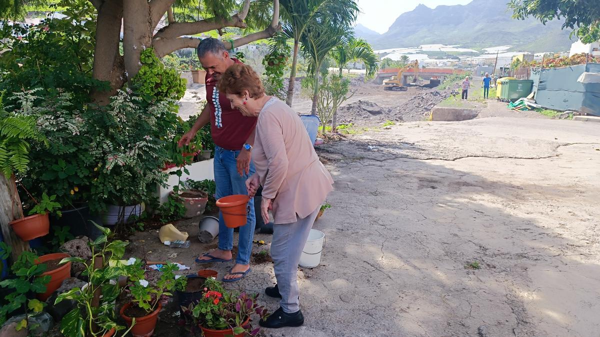 Marina Santana y Román Ojeda, ayer, cuidando de las flores en la vivienda familiar junto al barranco de Tocodomán, en obras al fondo.