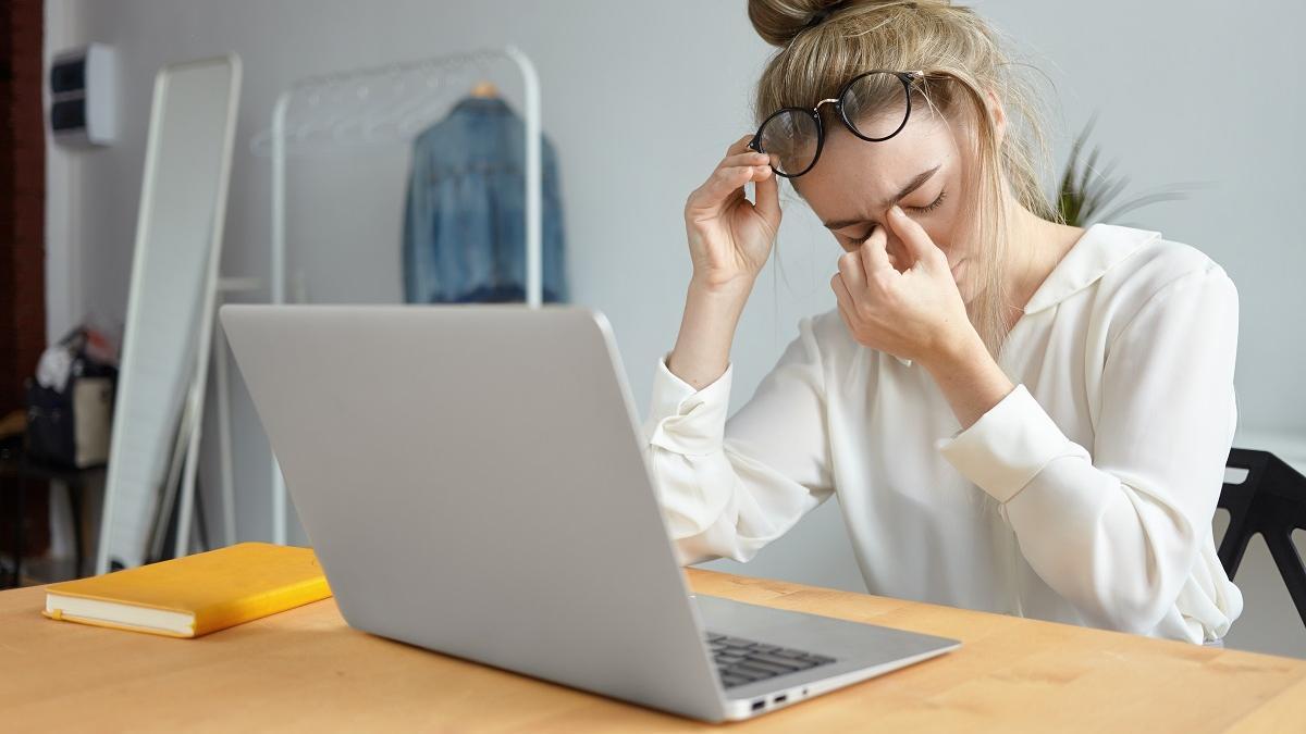 Una mujer sufre un dolor de cabeza en el trabajo.