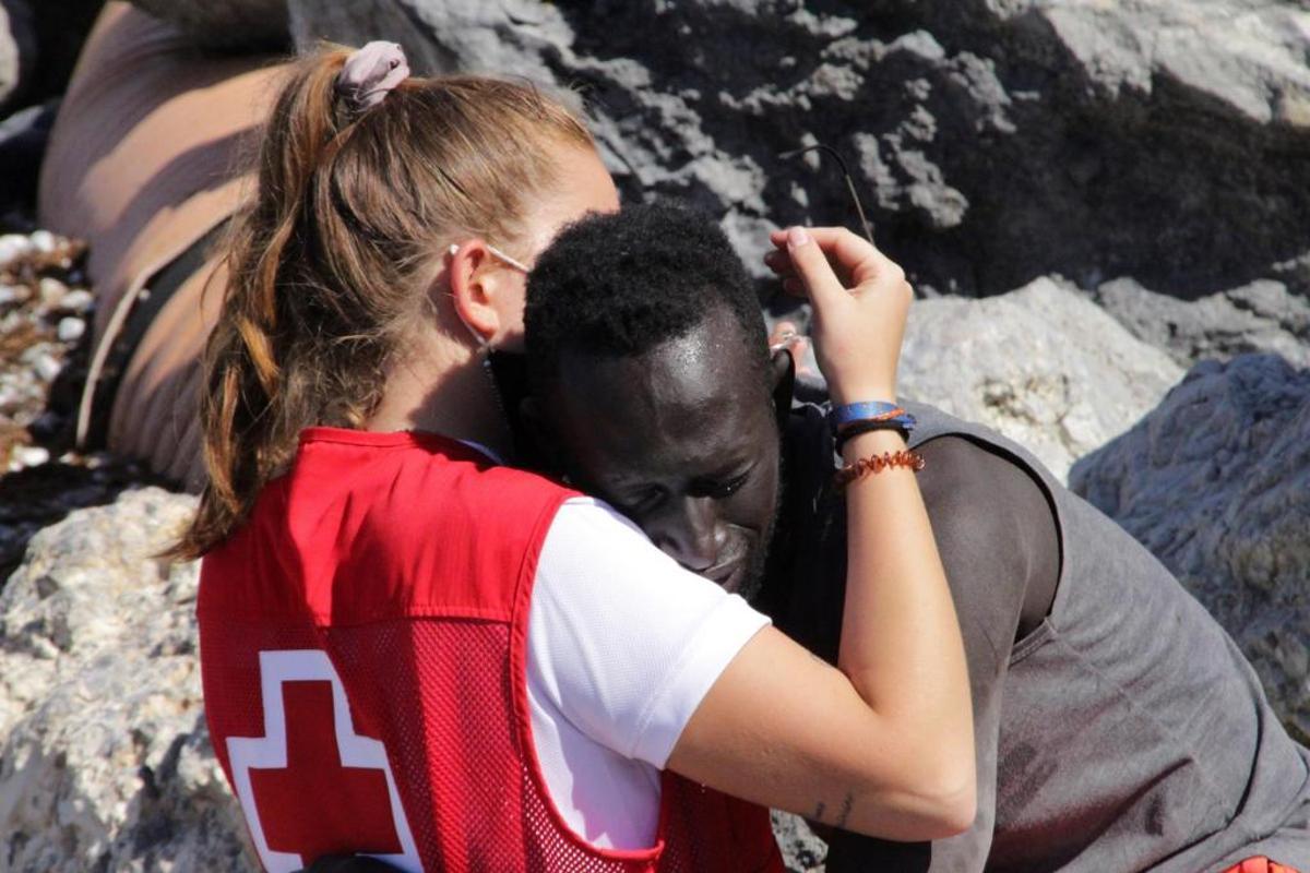 18/5/2021. En una imagen de solidaridad que dio la vuelta al mundo, una voluntaria de la Cruz Roja consuela a un inmigrante senegalés que alcanzó la costa de Ceuta durante la crisis migratoria de mayo.