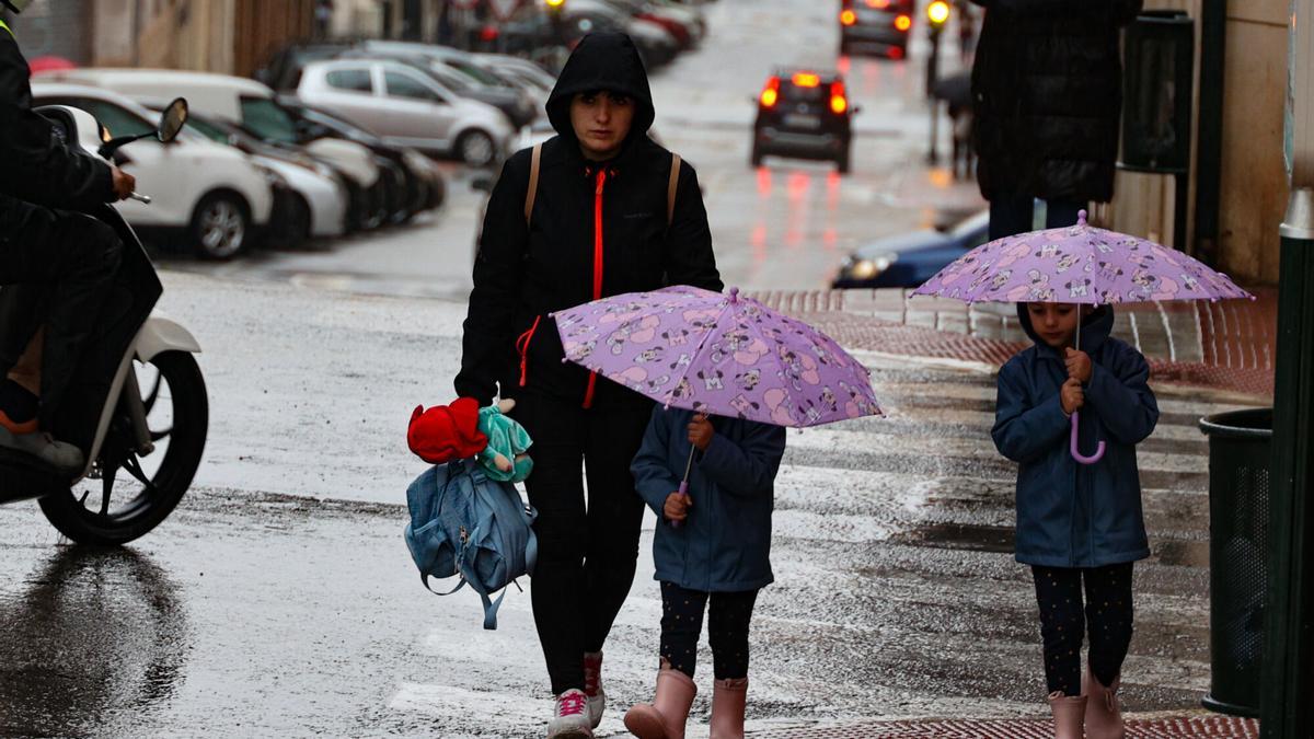 Una familia de camino al colegio con lluvia en Alcoy