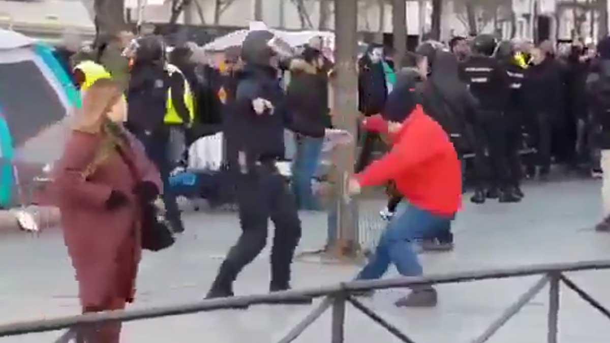 Un hombre se cae, o se tira, al suelo cuando un agente de la Policía Nacional le toca el brazo