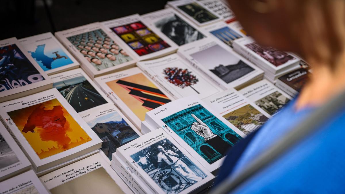 Una persona observant llibres en una parada per Sant Jordi