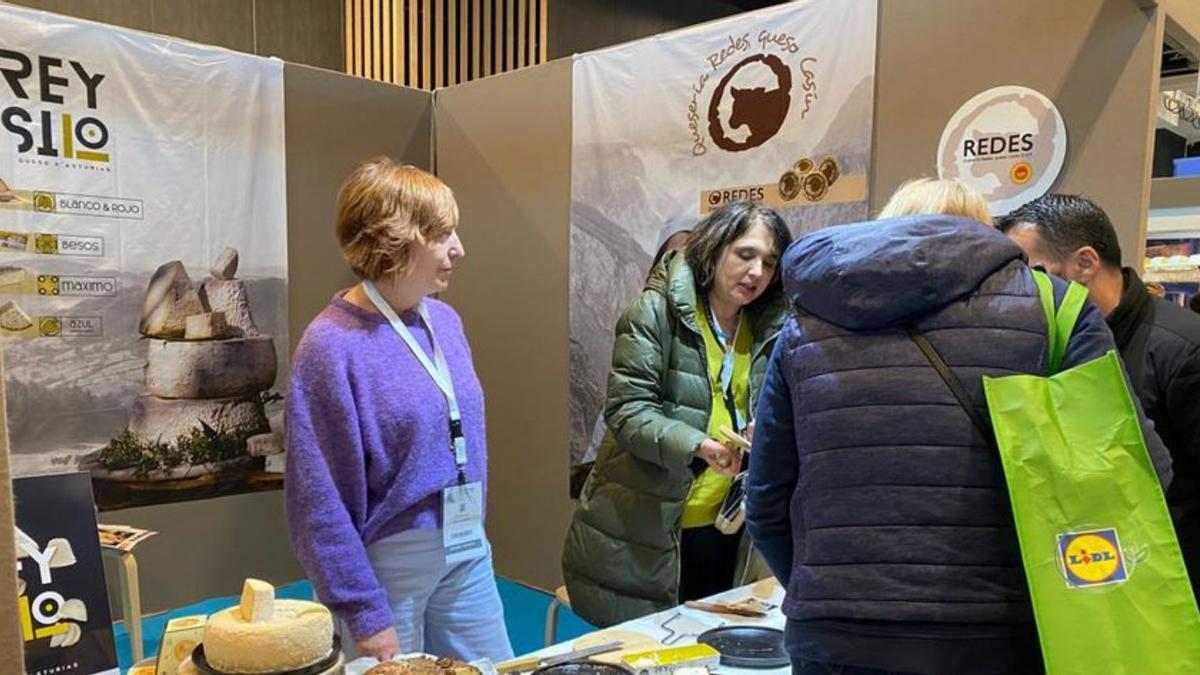 Natalia Lobeto, a la derecha, dando a probar queso en el expositor asturiano en el Salon du Fromage, en París.