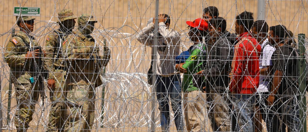 Migrants stand near the border wall after having crossed the U.S.-Mexico border