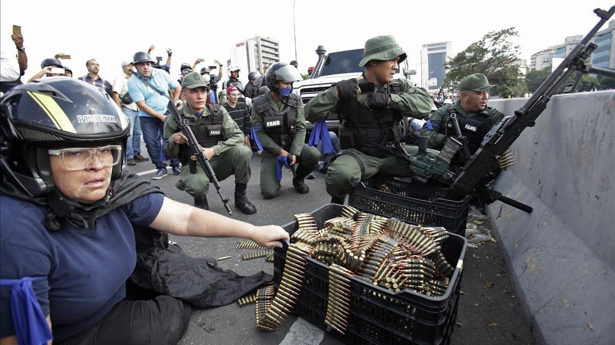 Una manifestante antigubernamental se sienta junto a las municiones utilizadas por las tropas rebeldes que se levantan contra el presidente Nicolas Maduro.