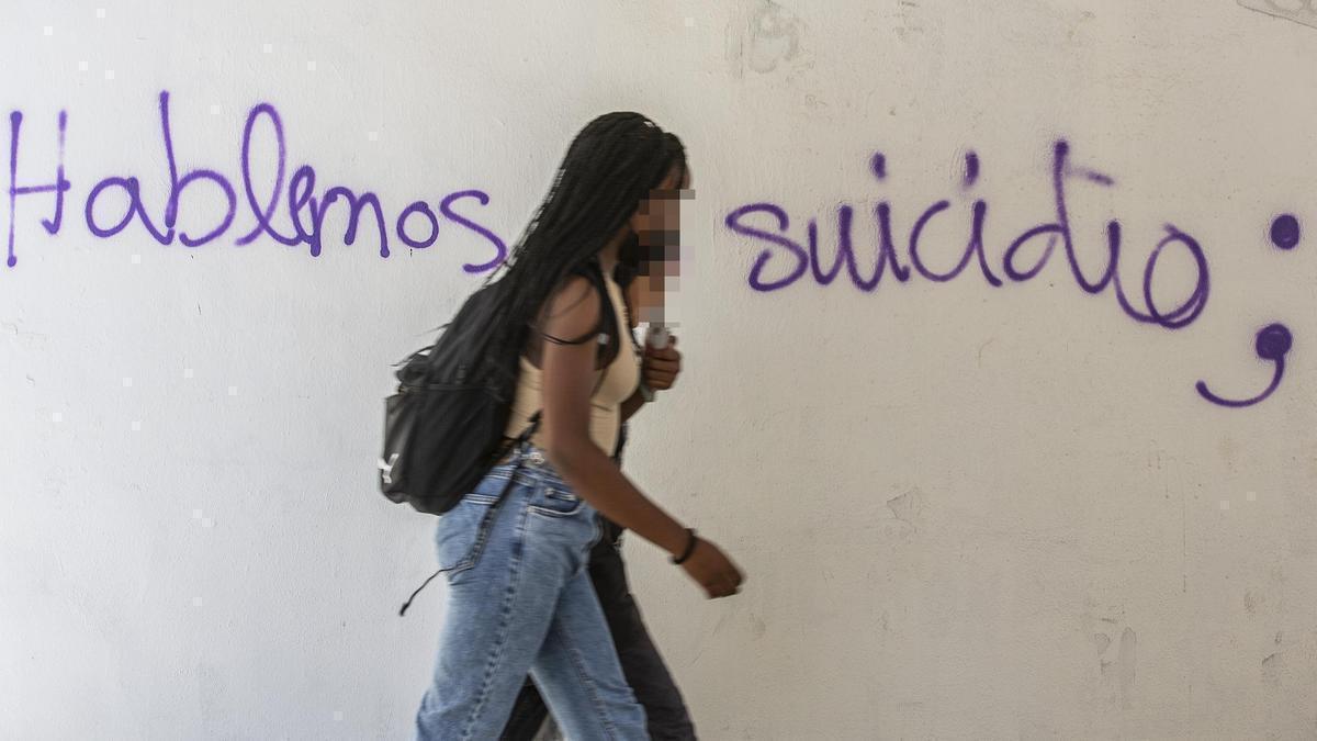 Una joven pasa anteuna pintada sobre el suicidio, en Alicante.