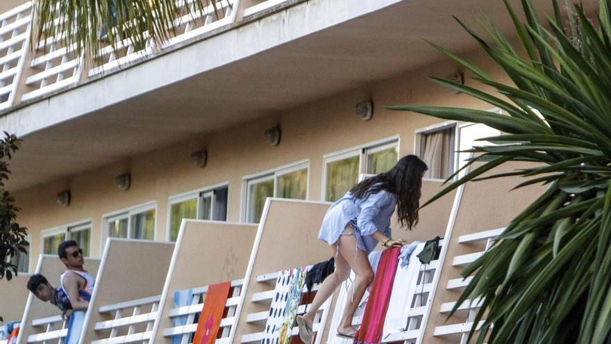 Una joven turista pasa de un balcón a otro en un hotel