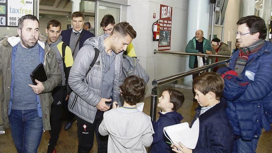 Hugo Mallo atiende a unos jóvenes aficionados del Celta, ayer, en el aeropuerto de Peinador. // Alba Villar
