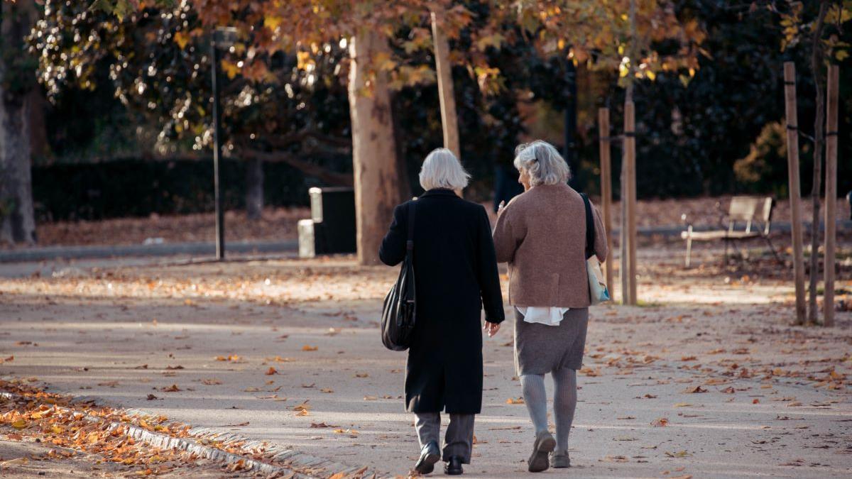 Dos ancianas pasean por un parque.