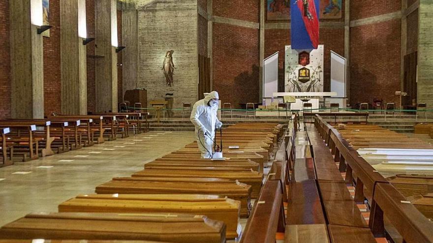 Un soldado desinfecta entre una de las filas de ataúdes que llenan una iglesia de Bérgamo.