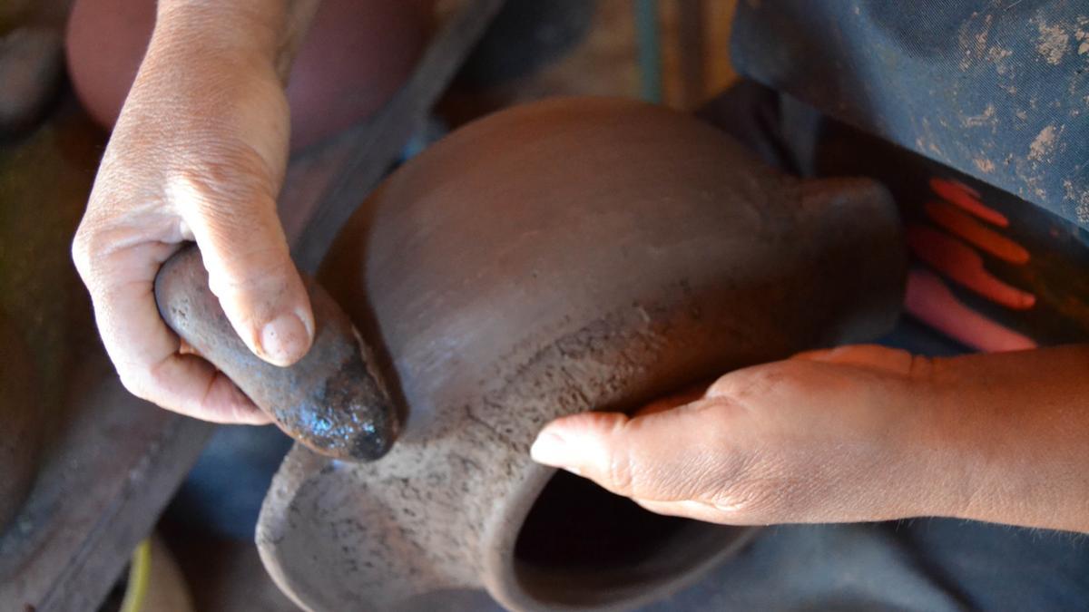 Un artesano trabaja con una vasija de barro.