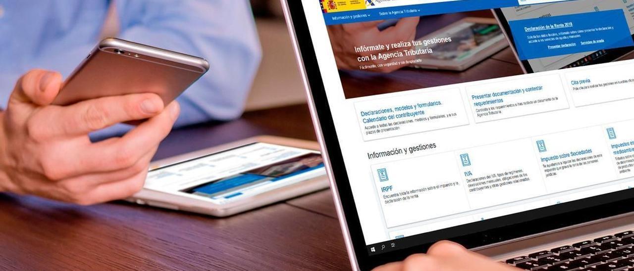 Dos personas consultan la web de la Agencia Tributaria a través de un ordenador y un móvil. / EL PERIÓDICO