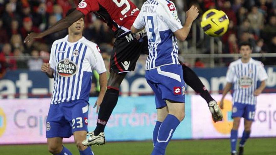 Webó mira el balón tras rematar de cabeza entre dos defensas del Deportivo.