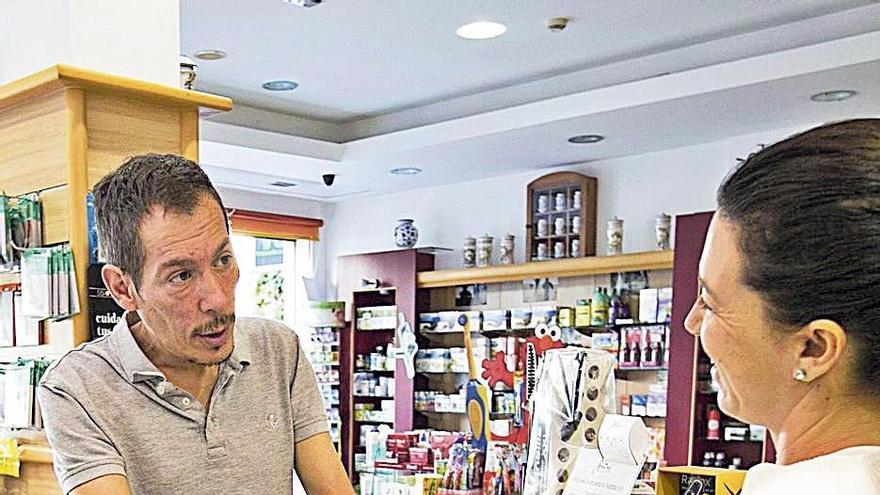 Un cliente recibe una bolsa con medicamentos en una farmacia de Canarias.