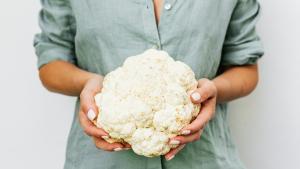 Una mujer sujeta una coliflor. 