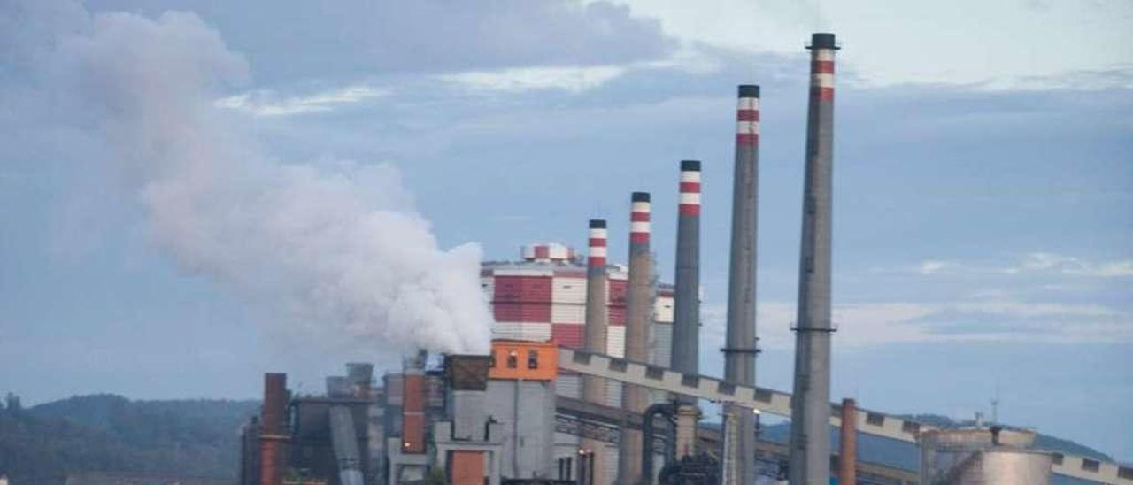 Peatones por el paseo de la ría; con las baterías de coque de Arcelor-Mittal, al fondo.