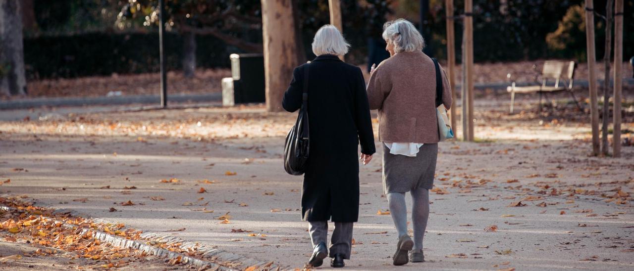 Dos mujeres mayores pasean por un parque.