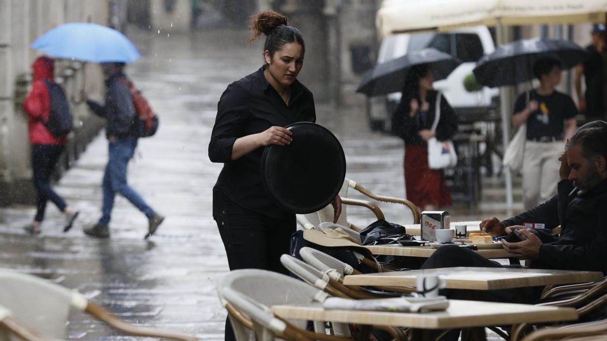 Una camarera atiende una terraza de Galicia.