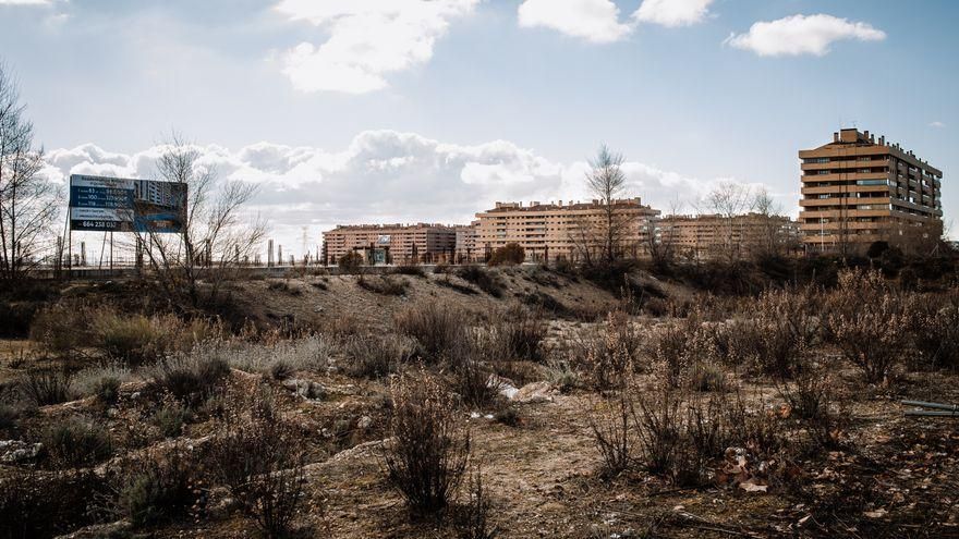 Un cartel anunciando un edificio de nueva construcción en El Quiñón junto a varios inmuebles levantados hace años.