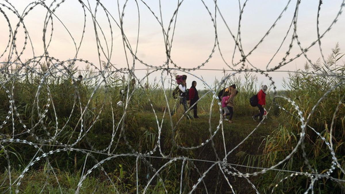 Inmigrantes vistos desde la valla alambrada que se terminó de construir este fin de semana en la frontera entre Hungría y Serbia.