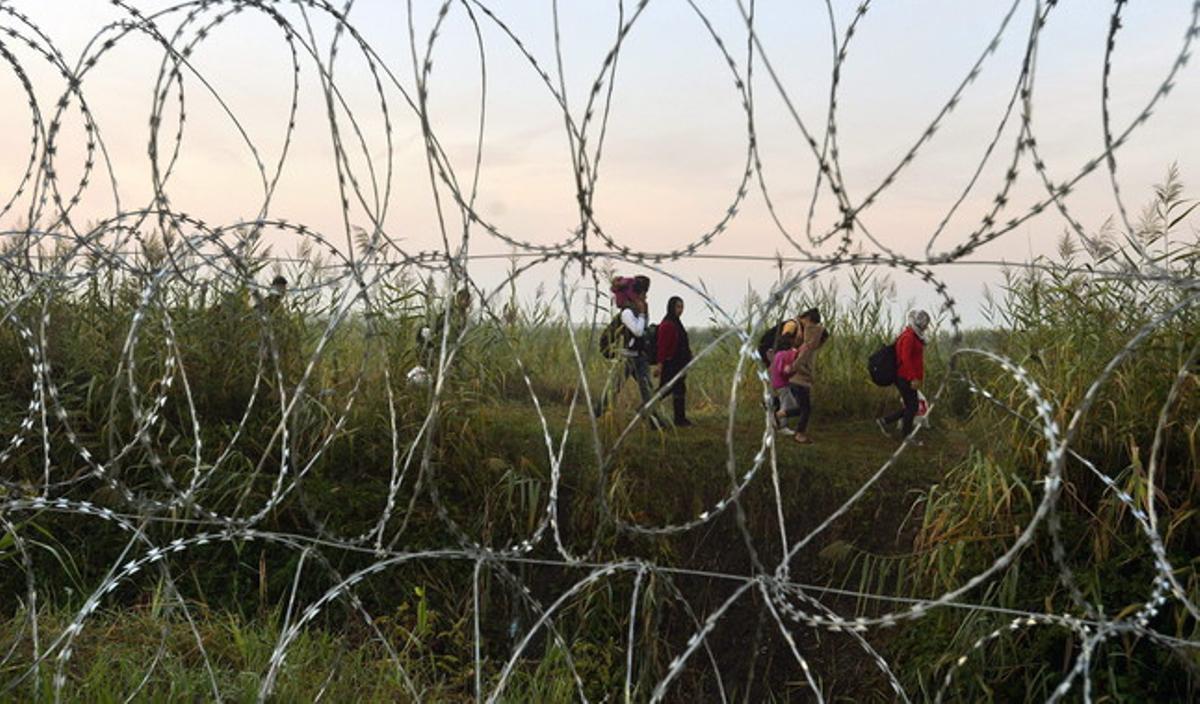 Immigrants vistos des de la tanca filat de ganivetes que es va acabar de construir aquest cap de setmana en la frontera entre Hongria i Sèrbia.