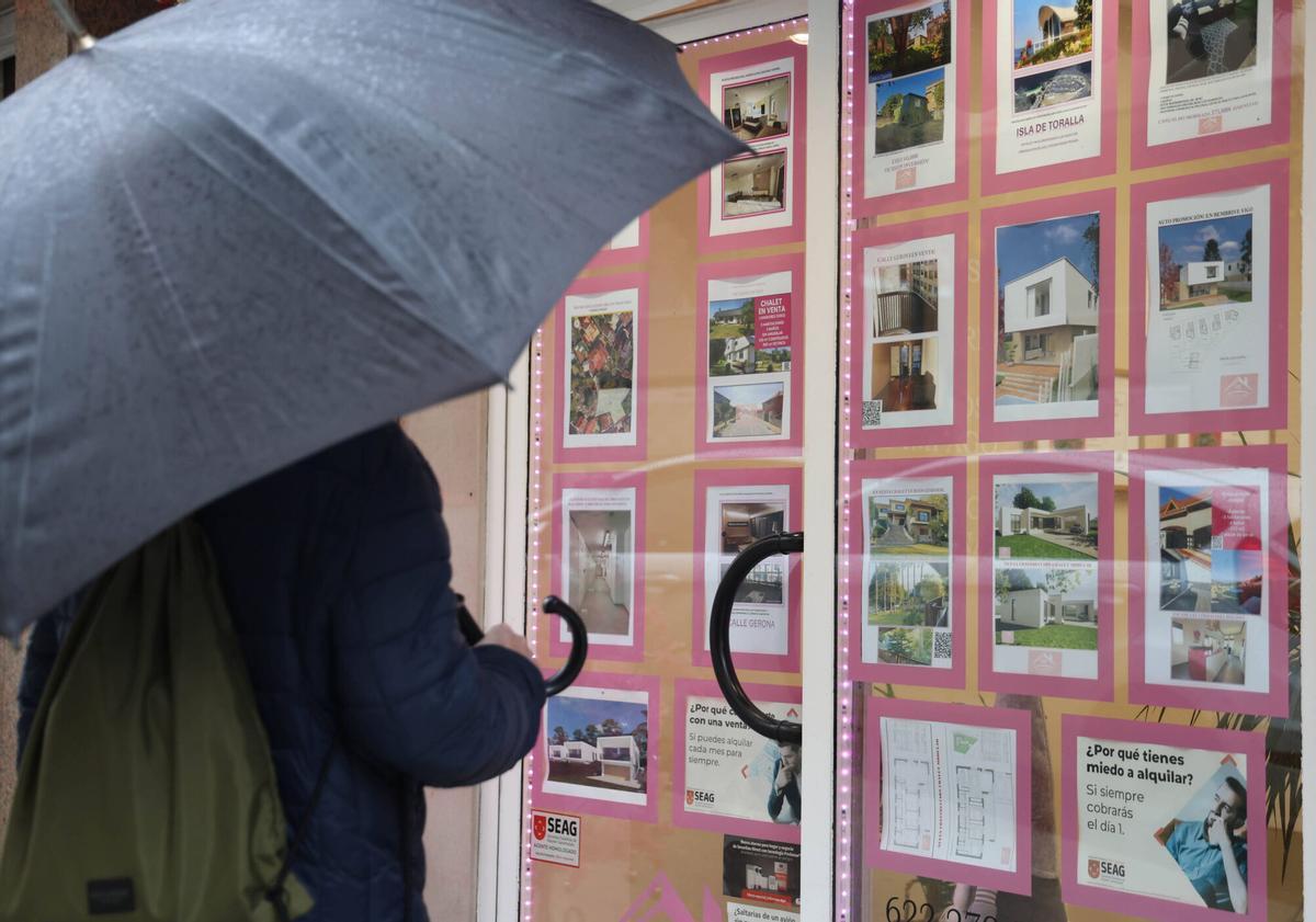 Una persona mirando el escaparate de una inmobiliaria en Vigo.
