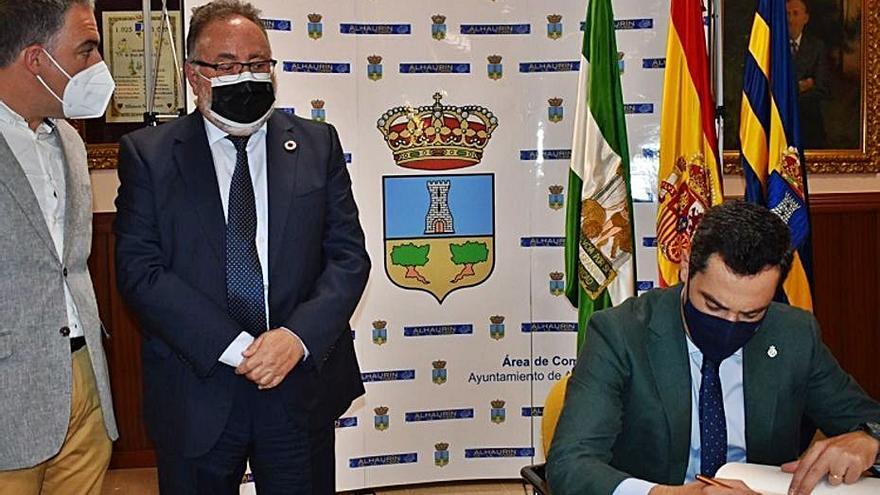 El presidente andaluz, Juanma Moreno, firma en el libro oficial