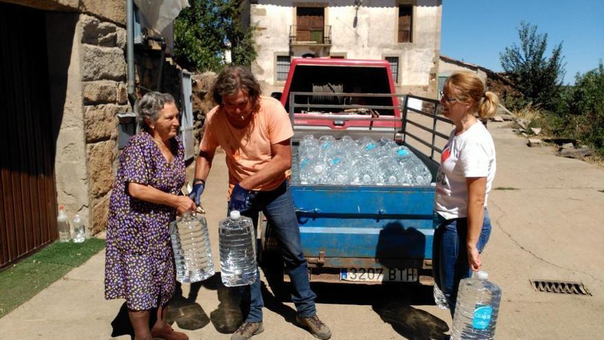 Vecinas de Arcillera reciben las garrafas de agua potable durante el pasado verano.