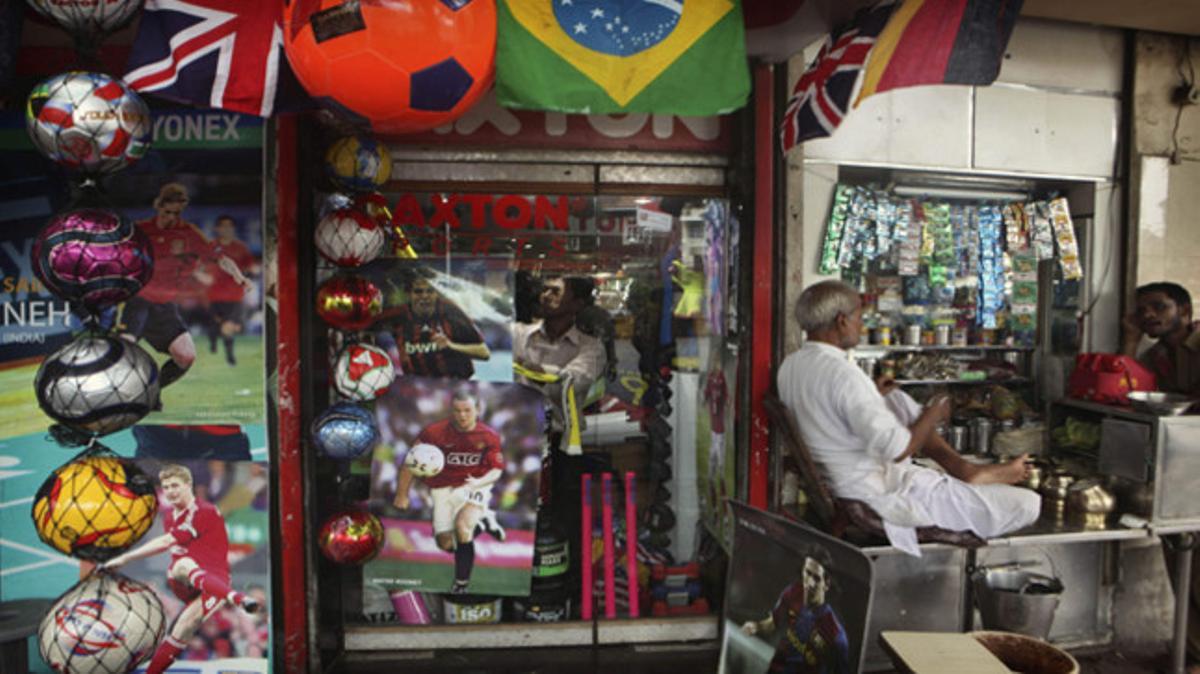 Habitants de tots els països seguiran el Mundial. A la imatge, un venedor indi ha posat cartells de jugadors de futbol a la portada del seu comerç, a Bombai.