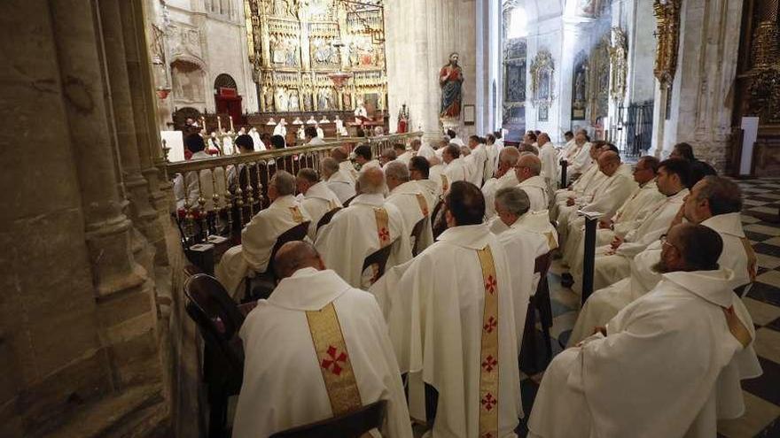 Arriba, varios de los sacerdotes asistentes a la misa crismal. A la izquierda, las jarras de los óleos.