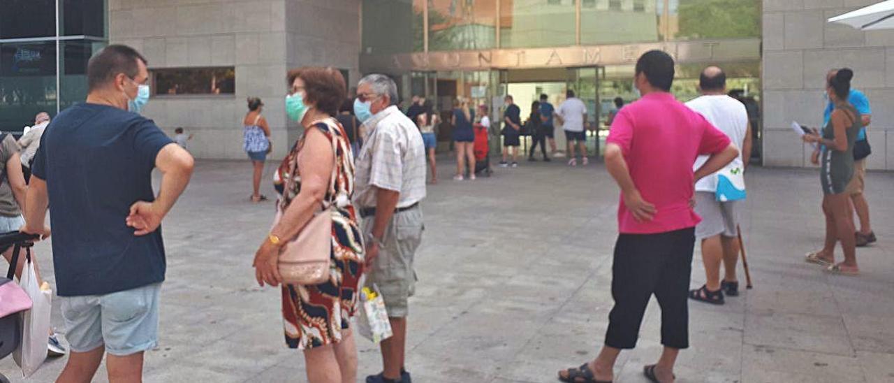 Auxiliares de servicio atienden a la entrada del Ayuntamiento donde ayer se acrecentaron las colas de vecinos.