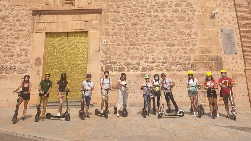 Los participantes en la primera ruta con patinete eléctrico por la Vall d&#039;Uixó en una de las paradas, frente a la iglesia del Santo Ángel.