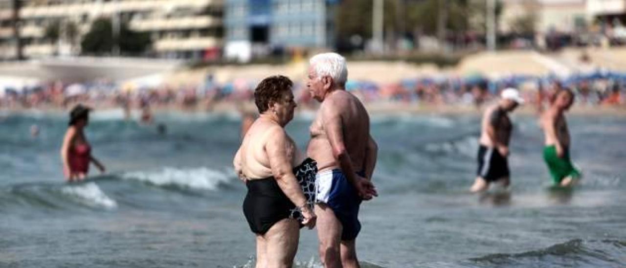 Turistas mayores toman un baño en la playa de Poniente de Benidorm, durante la pasada campaña del Imserso