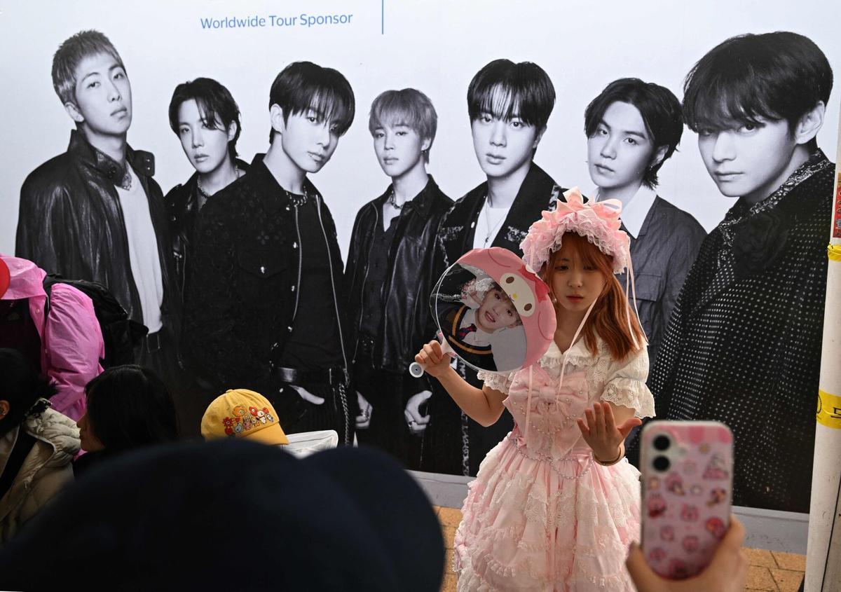 Una mujer posa para una foto frente a una pancarta del grupo de K-pop BTS en un estadio donde el grupo se presentará en Goyang el 9 de abril de 2026. Las megaestrellas surcoreanas del K-pop, BTS, darán inicio a su gira mundial el 9 de abril, aprovechando el éxito de su álbum de regreso y una presentación histórica en el corazón de Seúl. (Foto de Jung Yeon-je / AFP)
