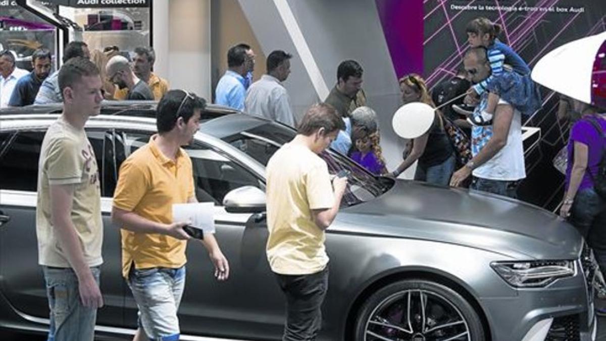 Varios jóvenes observan un modelo de Audi en el Salón de Barcelona.