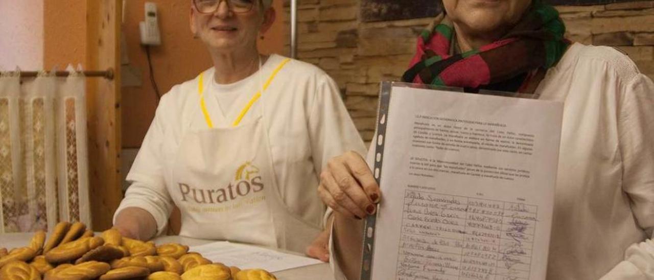 Emilia Fernández y Antonia Durán en su pastelería de Candás, con marañuelas y firmas.