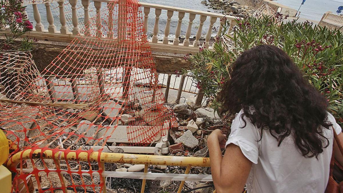 Daños en un escalera de bajada a la playa y palmera que los vecinos han sostenido con piedras. | PILAR CORTÉS