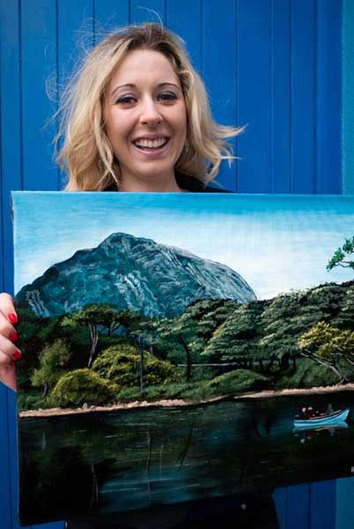 Mujer en Tully muestra un pintura del paisaje de Connemara.