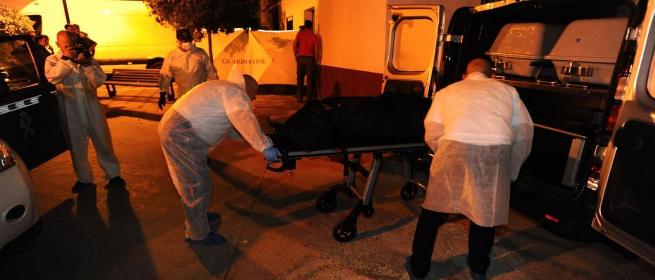 Los empleados de la funeraria introducen el cadáver de la víctima en el furgón en presencia de la Guardia Civil.