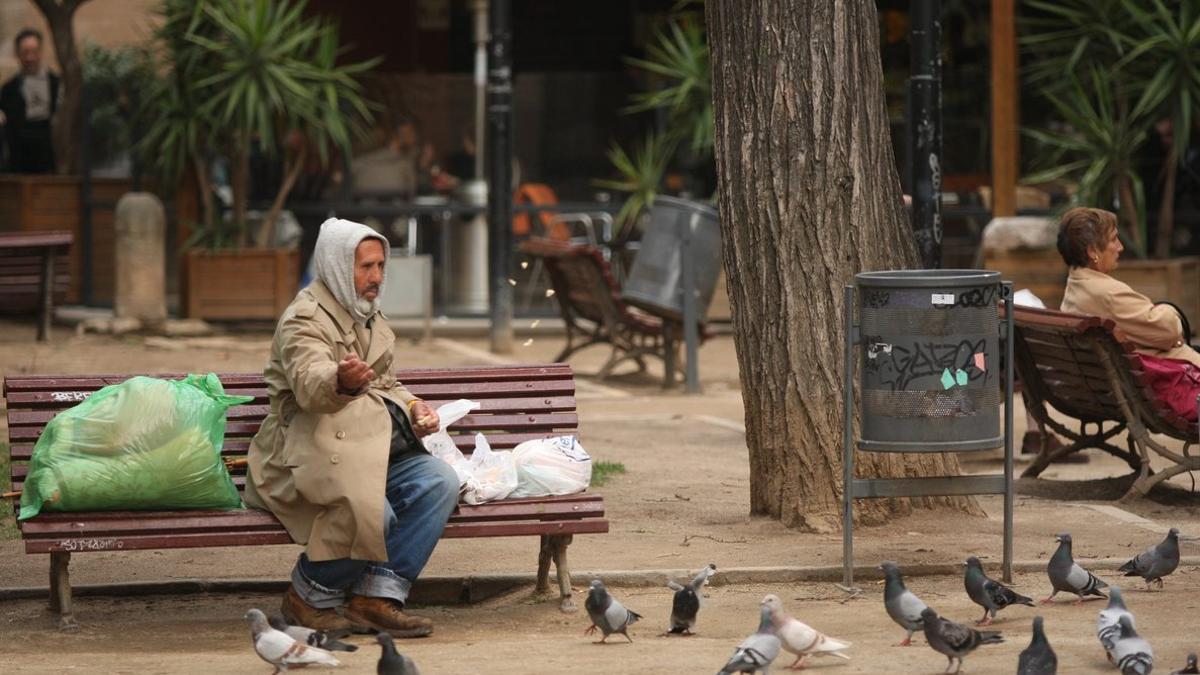 Una persona sin hogar dando de comer a las palomas